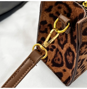 Detailed close-up of leopard print faux fur texture and gold metal hardware on the handbag