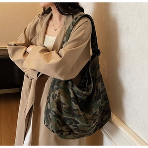 Détail d'un grand sac fourre-tout en toile camouflage porté avec un trench décontracté