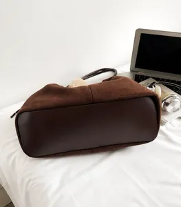 Close-up of brown suede tote bag featuring premium stitching and contrast leather bottom