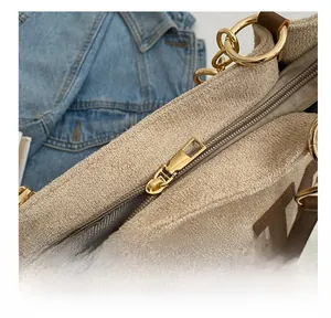 Detailed view of gold metal zipper and inner lining on beige textured tote bag
