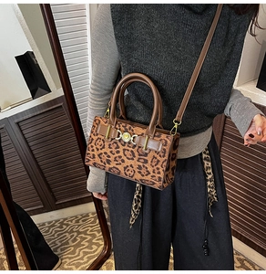 Detail shot of leopard print handbag with brown leather straps and gold metal hardware
