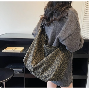 Détail d'un grand sac cabas en toile à imprimé léopard porté à l'épaule de façon décontractée
