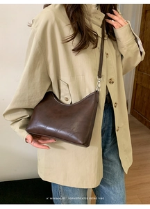 Close-up of minimalist dark brown leather bucket bag on model in khaki coat