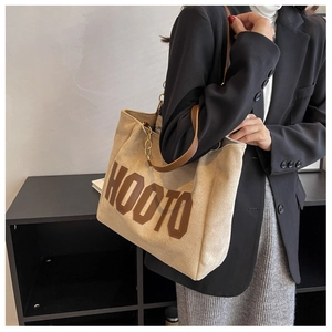 Detail view of large beige tote bag with HOOTO lettering and gold chain accent