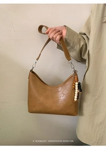 Detail of caramel retro half-moon bag featuring unique wooden bead tassel and matte leather