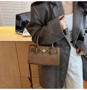 Detail of a brown suede rectangular crossbody bag with a vintage gold clasp