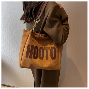 Close-up of brown suede tote bag featuring HOOTO leather patch and gold chain strap