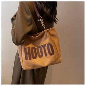 Close-up of brown suede tote bag featuring large HOOTO letter applique and gold chain straps
