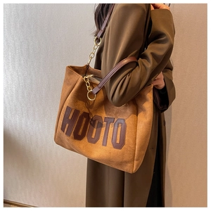Detail of vintage brown suede tote bag with HOOTO letter patch and metal chain strap