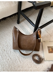 Detail of a brown retro bucket bag with colorful wooden beads and leather texture