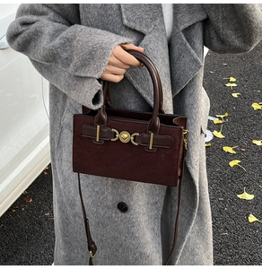 Detail of dark brown faux suede handbag with golden heart clasp and vintage straps