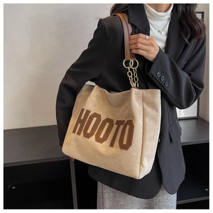 Close-up of HOOTO tote bag detail showing beige fabric with brown leather strap and gold ring