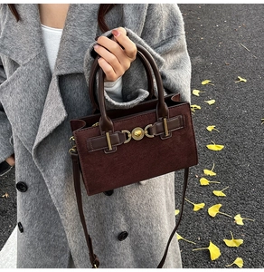 Brown suede crossbody bag with heart buckle shown on model in autumn park setting