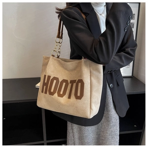 Beige canvas tote bag with brown leather HOOTO patch and gold chain strap shown on shoulder
