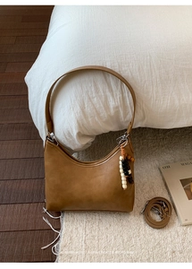 Detail view of brown faux leather crescent bag with wooden bead charm and strap