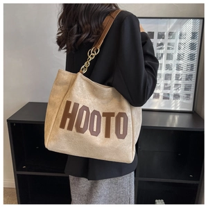 Detail of HOOTO tote bag showing suede texture, brown leather handles, and gold chain strap