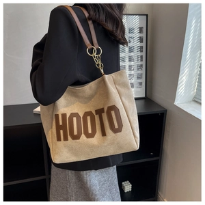 Detail of HOOTO beige canvas tote bag with brown leather lettering and gold chain strap