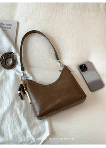 Detail view of brown retro hobo bucket bag with wooden bead charm and dual straps