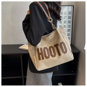 Detail showing high-capacity khaki suede tote bag with brown leather straps and gold chains