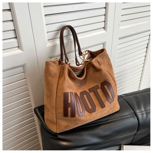 Close-up of brown suede tote bag featuring HOOTO leather patch and gold ring hardware