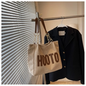 Detailed view of large tote bag featuring HOOTO leather lettering and gold chain strap