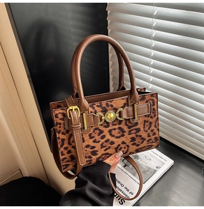 Detail of leopard print handbag with golden ring buckle and brown leather strap on a table