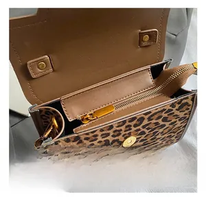 Close-up showing leopard print texture, golden magnetic buckle, and interior zip pocket