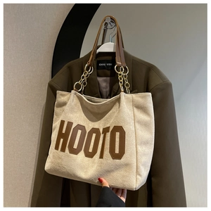 Detail of cream suede tote bag with HOOTO brown leather patch and gold chain strap