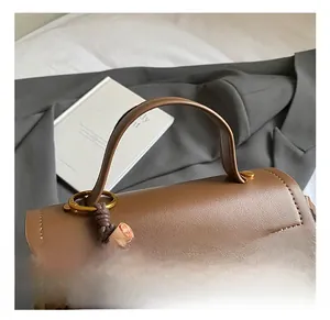 Detailed close-up of brown leather handbag with leopard print and wooden bead tassel