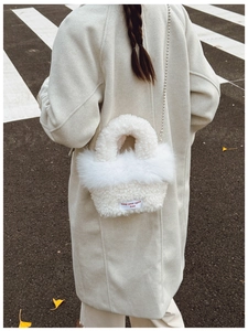 Detail of white faux shearling crossbody bag with pearl chain and spirit text label