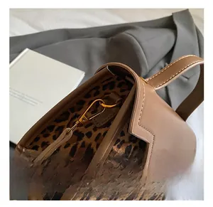 Detail of high-quality gold metal hooks on brown leather handbag with leopard pattern