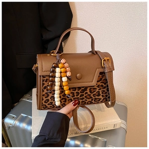 Detail of leopard print patchwork handbag with bohemian wooden bead tassel and gold hardware