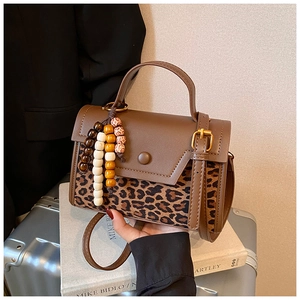 Close-up of vintage handbag with leopard print panel and ethnic wooden bead charms