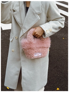Detail of pink faux shearling texture with keep your spirit free woven label on a bag