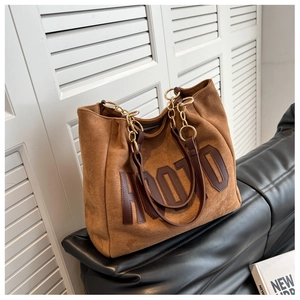 Detail of brown suede tote bag with HODO lettering and golden metal chain strap