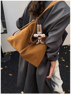 Dettaglio della borsa tote marrone con pieghe geometriche e ciondolo di peluche