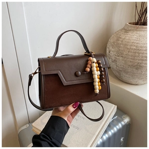 Detail of a vintage dark coffee handbag with mixed leather textures and wooden beads