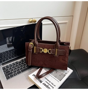 Detailed view of suede and leather crossbody bag featuring a golden heart-shaped twist lock