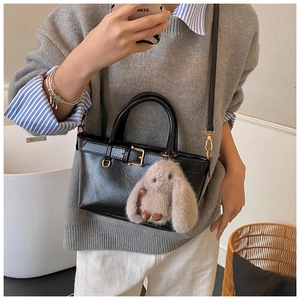 Détail d'un sac seau noir en cuir avec boucle rétro et breloque lapin en peluche