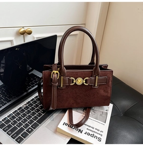 Close-up of matte dark brown leather tote with golden heart buckle and smooth handles