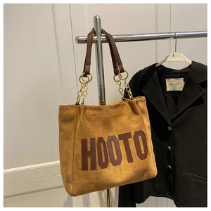 Detail of suede tote bag featuring leather HOOTO patch and gold chain handles