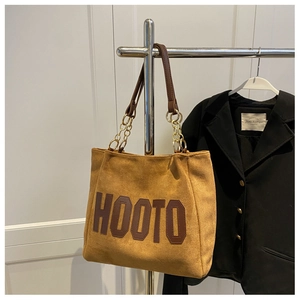 Detail of suede tote bag with HOOTO letter print and elegant gold chain handles