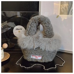 Detail of grey faux shearling handbag with embroidery tag and metal chain strap