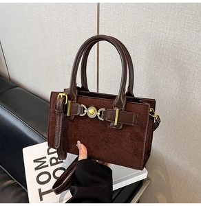 Close-up of matte dark brown suede handbag featuring a gold heart-shaped metal lock