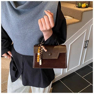 Detailed view of brown spliced small square handbag with vintage colorful wooden beads