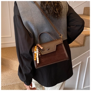 Detail of vintage brown leather handbag featuring mixed textures and colorful wooden beads