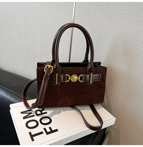 Detail of dark brown suede crossbody bag with gold buckle and circular ring accent