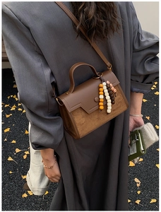 Detail view of retro brown leather crossbody bag with suede panel and wooden bead charms