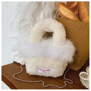 Close-up of white fleece handbag with faux fur trim and silver bead chain strap