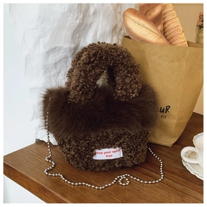 Detail of dark brown plush shoulder bag with faux fox fur trim and silver bead chain